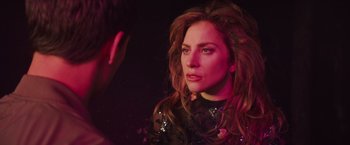 Movie still from “A Star Is Born” (2018), directed by Bradley Cooper – A woman in a black dress looking at the camera; Close Up shot, Over the shoulder angle