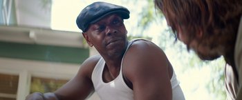 Movie still from “A Star Is Born” (2018), directed by Bradley Cooper – A man wearing a hat and a white tank top; Close Up shot, Over the shoulder angle