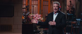 Movie still from “A Star Is Born” (2018), directed by Bradley Cooper – A man in a black suit and white shirt is talking; Medium shot, Over the shoulder angle