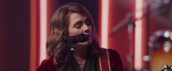 Movie still from “A Star Is Born” (2018), directed by Bradley Cooper – A woman is singing into a microphone on a stage; Close Up shot, Low angle