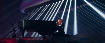 Movie still from “A Star Is Born” (2018), directed by Bradley Cooper – A woman standing in front of a grand piano in front of lights; Extreme Wide shot, Low angle