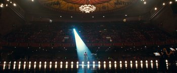 Movie still from “A Star Is Born” (2018), directed by Bradley Cooper – A man standing on a stage in front of lights; Extreme Wide shot, High angle