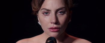 Movie still from “A Star Is Born” (2018), directed by Bradley Cooper – A person holding a microphone; Close Up shot, High angle
