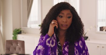 A woman talking on a cell phone while wearing a purple jacket
