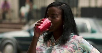 Movie still from “A Thousand and One” (2023), directed by A.V. Rockwell – A woman drinking from a pink cup; Close Up shot, Over the shoulder angle