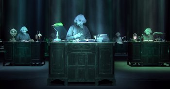An old man sitting at a desk in front of a lamp