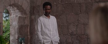 A man standing in front of a brick wall with his hands in his pockets