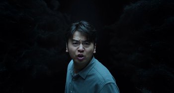 Movie still from “A Writer's Odyssey” (2021), directed by Yang Lu – A man in a blue shirt is making a funny face; Medium shot, Low angle