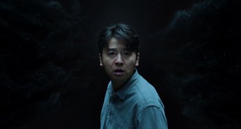 Movie still from “A Writer's Odyssey” (2021), directed by Yang Lu – A man in a blue shirt is looking at the camera; Medium shot, Overhead angle