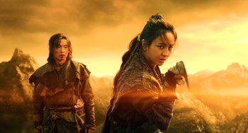 Movie still from “A Writer's Odyssey” (2021), directed by Yang Lu – Two people standing next to each other on a field; Medium shot, Low angle