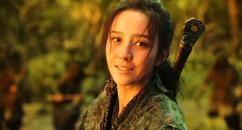 Movie still from “A Writer's Odyssey” (2021), directed by Yang Lu – A young woman in a green jacket holding a stick; Close Up shot, Low angle