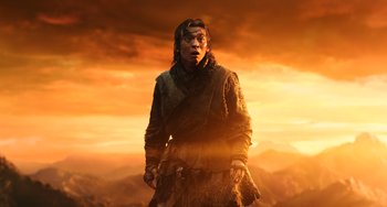 Movie still from “A Writer's Odyssey” (2021), directed by Yang Lu – A man standing in front of an orange sky; Medium shot, Low angle