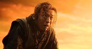 Movie still from “A Writer's Odyssey” (2021), directed by Yang Lu – A man with long brown hair is looking at the camera; Close Up shot, Low angle