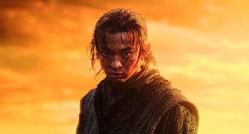 Movie still from “A Writer's Odyssey” (2021), directed by Yang Lu – A man with long brown hair standing in front of an orange sky; Close Up shot, Low angle