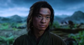 Movie still from “A Writer's Odyssey” (2021), directed by Yang Lu – A man with long black hair wearing a green robe; Close Up shot, Low angle