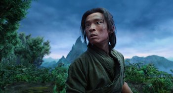Movie still from “A Writer's Odyssey” (2021), directed by Yang Lu – A man in a green shirt is standing in front of a mountain; Close Up shot, Low angle