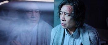 Movie still from “A Writer's Odyssey” (2021), directed by Yang Lu – A man with bruises on his face looking out a window; Close Up shot, Low angle