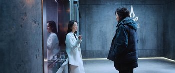 Movie still from “A Writer's Odyssey” (2021), directed by Yang Lu – Two women standing next to each other in front of a glass case; Medium shot, Over the shoulder angle