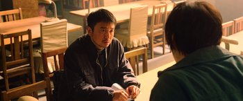 Movie still from “A Writer's Odyssey” (2021), directed by Yang Lu – A man sitting in front of a woman at a table; Medium shot, Over the shoulder angle