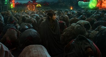 Movie still from “A Writer's Odyssey” (2021), directed by Yang Lu – A man sitting in the middle of a large group of people; Wide shot, High angle