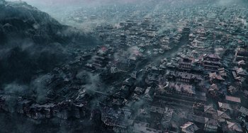 Movie still from “A Writer's Odyssey” (2021), directed by Yang Lu – An aerial view of a city with smoke billowing out of it; Extreme Wide shot, High angle