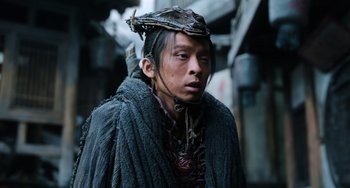 Movie still from “A Writer's Odyssey” (2021), directed by Yang Lu – A man wearing a hat and a black coat; Close Up shot, Low angle