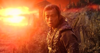 Movie still from “A Writer's Odyssey” (2021), directed by Yang Lu – A man in a brown jacket standing in front of a sunset; Close Up shot, Low angle