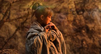 Movie still from “A Writer's Odyssey” (2021), directed by Yang Lu – A young girl is wrapped up in a blanket and holding a cell phone to her ear; Close Up shot, High angle