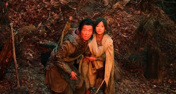 Movie still from “A Writer's Odyssey” (2021), directed by Yang Lu – A man standing next to a young girl holding a sword; Medium shot, High angle