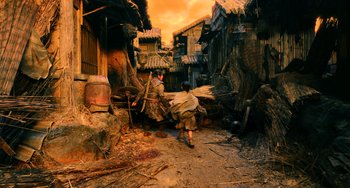 Movie still from “A Writer's Odyssey” (2021), directed by Yang Lu – Two men are walking down the street with a bunch of sticks; Wide shot, High angle