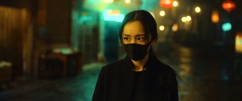 Movie still from “A Writer's Odyssey” (2021), directed by Yang Lu – A woman wearing a black mask standing in a dark room; Close Up shot, Low angle