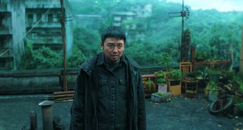 Movie still from “A Writer's Odyssey” (2021), directed by Yang Lu – A man standing in the middle of a forest; Medium shot, Low angle