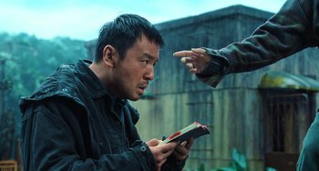 Movie still from “A Writer's Odyssey” (2021), directed by Yang Lu – A man holding an open book in front of another man; Medium shot, Over the shoulder angle