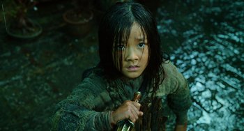 Movie still from “A Writer's Odyssey” (2021), directed by Yang Lu – A young girl holding a sword while standing in a river; Close Up shot, High angle