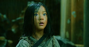Movie still from “A Writer's Odyssey” (2021), directed by Yang Lu – A little girl standing in the pouring rain; Close Up shot, Low angle