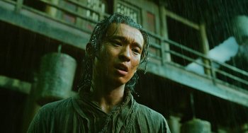 Movie still from “A Writer's Odyssey” (2021), directed by Yang Lu – A man standing in the pouring rain with his eyes closed; Close Up shot, Low angle