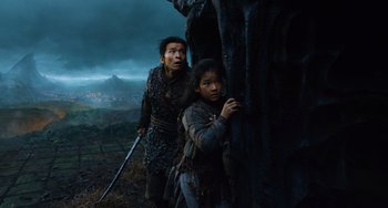 Movie still from “A Writer's Odyssey” (2021), directed by Yang Lu – A man and a woman are standing next to a tree; Medium shot, Low angle