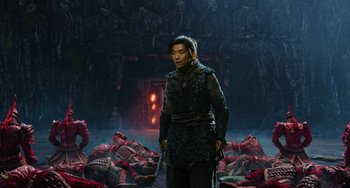 Movie still from “A Writer's Odyssey” (2021), directed by Yang Lu – A man standing next to a pile of corpses in a dark room; Wide shot, High angle