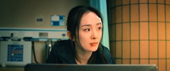 Movie still from “A Writer's Odyssey” (2021), directed by Yang Lu – A woman with a bandage on her head looking at a computer screen; Close Up shot, Over the shoulder angle