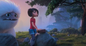 Movie still from “Abominable” (2019), directed by Todd Wilderman – A girl is standing next to a rock in a field; Wide shot, Over the shoulder angle
