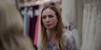 Movie still from “About Fate” (2022), directed by Marius Vaysberg – A woman with long blonde hair sitting in front of a row of dresses; Close Up shot, Over the shoulder angle