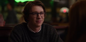 Movie still from “About Fate” (2022), directed by Marius Vaysberg – A young man wearing glasses and a sweater; Close Up shot, Over the shoulder angle
