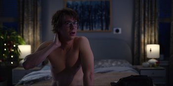 Movie still from “About Fate” (2022), directed by Marius Vaysberg – A shirtless man sitting on top of a bed in a bedroom; Medium shot, Over the shoulder angle