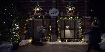 Movie still from “About Fate” (2022), directed by Marius Vaysberg – A woman standing in front of a store on a snowy night; Extreme Wide shot, High angle