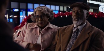 Movie still from “About Fate” (2022), directed by Marius Vaysberg – An older man and woman posing for a picture; Medium shot, Low angle