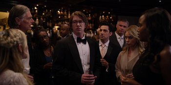 Movie still from “About Fate” (2022), directed by Marius Vaysberg – A group of people in suits and ties standing in front of a bar; Medium shot, Over the shoulder angle