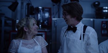 Movie still from “About Fate” (2022), directed by Marius Vaysberg – A man and a woman smiling at each other in front of an oven; Medium shot, Over the shoulder angle
