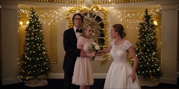 Movie still from “About Fate” (2022), directed by Marius Vaysberg – Two women and a man standing in front of a christmas tree; Medium shot, Over the shoulder angle