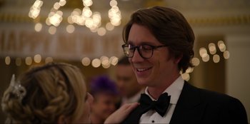 Movie still from “About Fate” (2022), directed by Marius Vaysberg – A man in a suit and bow tie smiling at a woman; Close Up shot, Over the shoulder angle