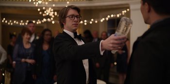 Movie still from “About Fate” (2022), directed by Marius Vaysberg – A man in a tuxedo holding a bottle of water in his hand; Close Up shot, Over the shoulder angle